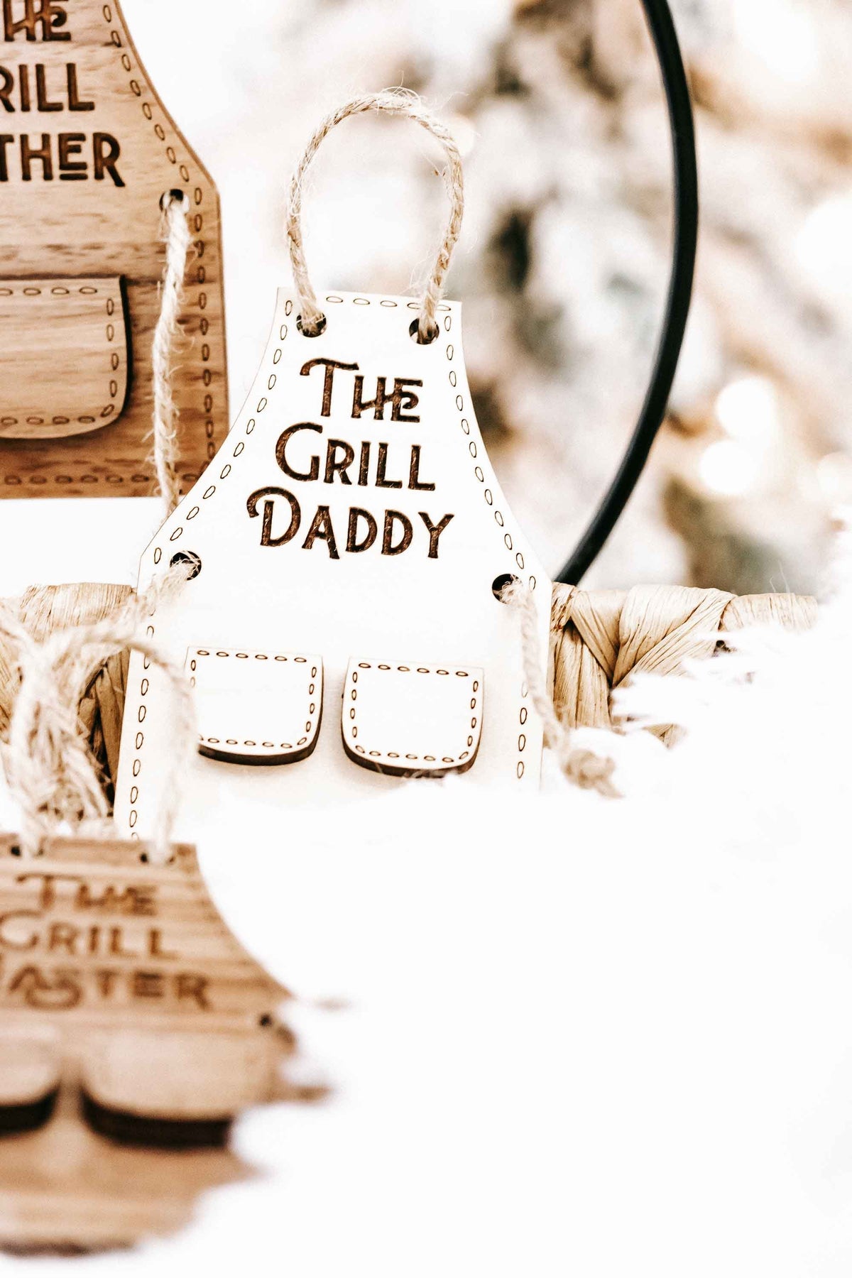 Close view of wood “The Grill Daddy” ornament with pocket cutouts and hanging rope.