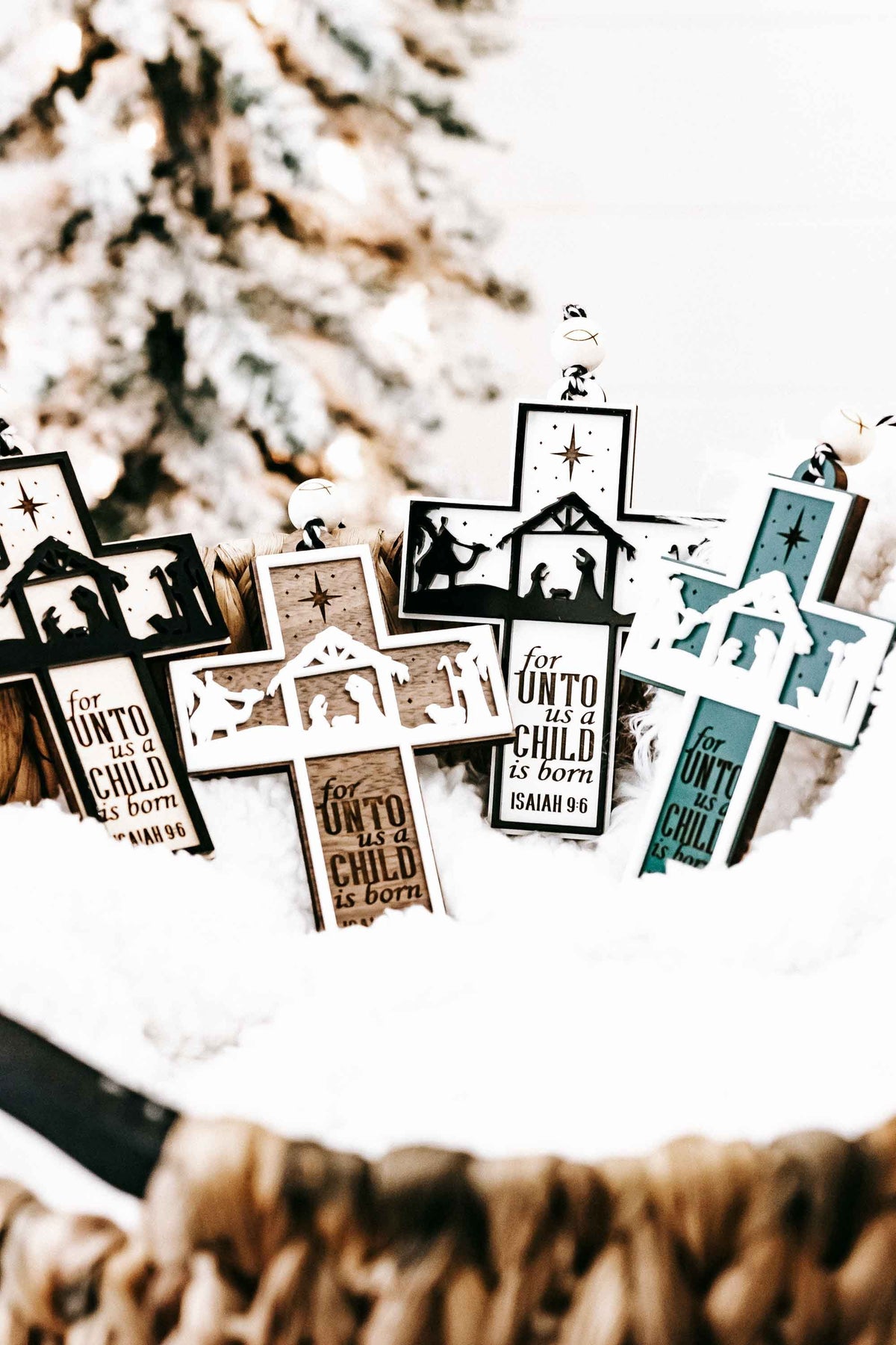 Mixed-color nativity cross ornaments with manger silhouettes and verse text “Isaiah 9:6”