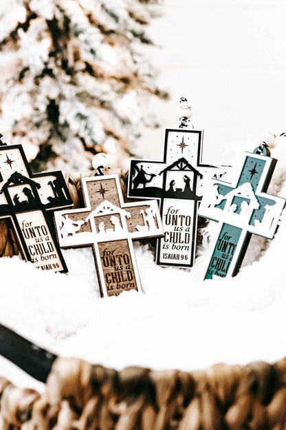 Mixed-color nativity cross ornaments with manger silhouettes and verse text “Isaiah 9:6”