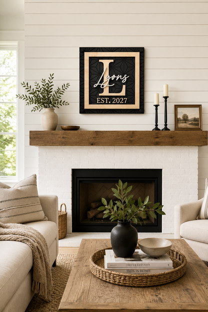 Framed black monogram family name sign with gold script and EST. 2027 on fireplace wall.