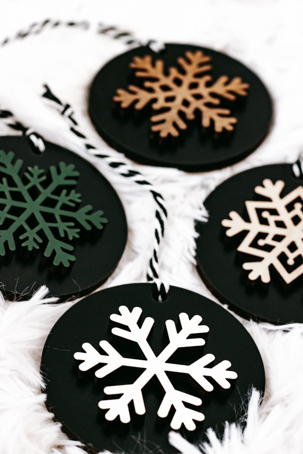 Black wooden ornament disc with a large white snowflake, plus green and tan accents