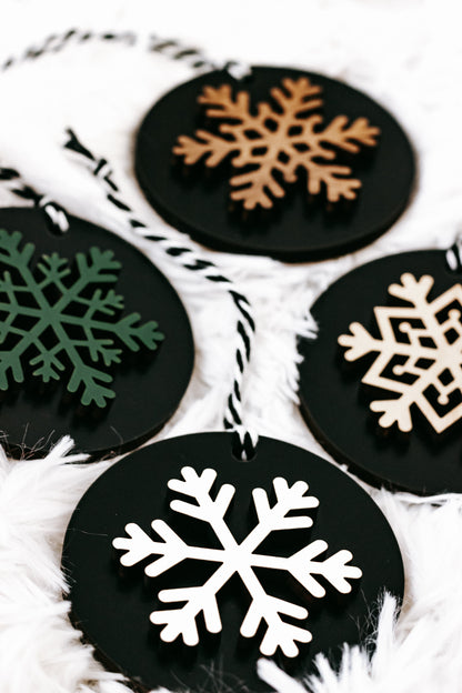 Black wooden ornament disc with a large white snowflake, plus green and tan accents
