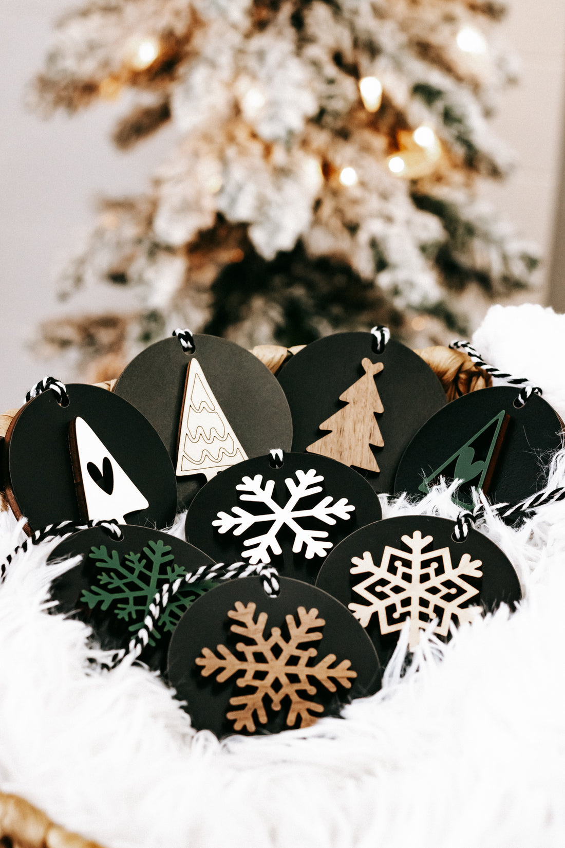 Black wooden ornament discs with snowflakes and a tan Christmas tree, hanging loops