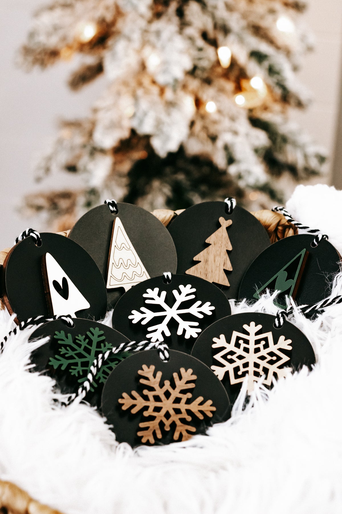 Black wooden ornament discs with snowflakes and a tan Christmas tree, hanging loops