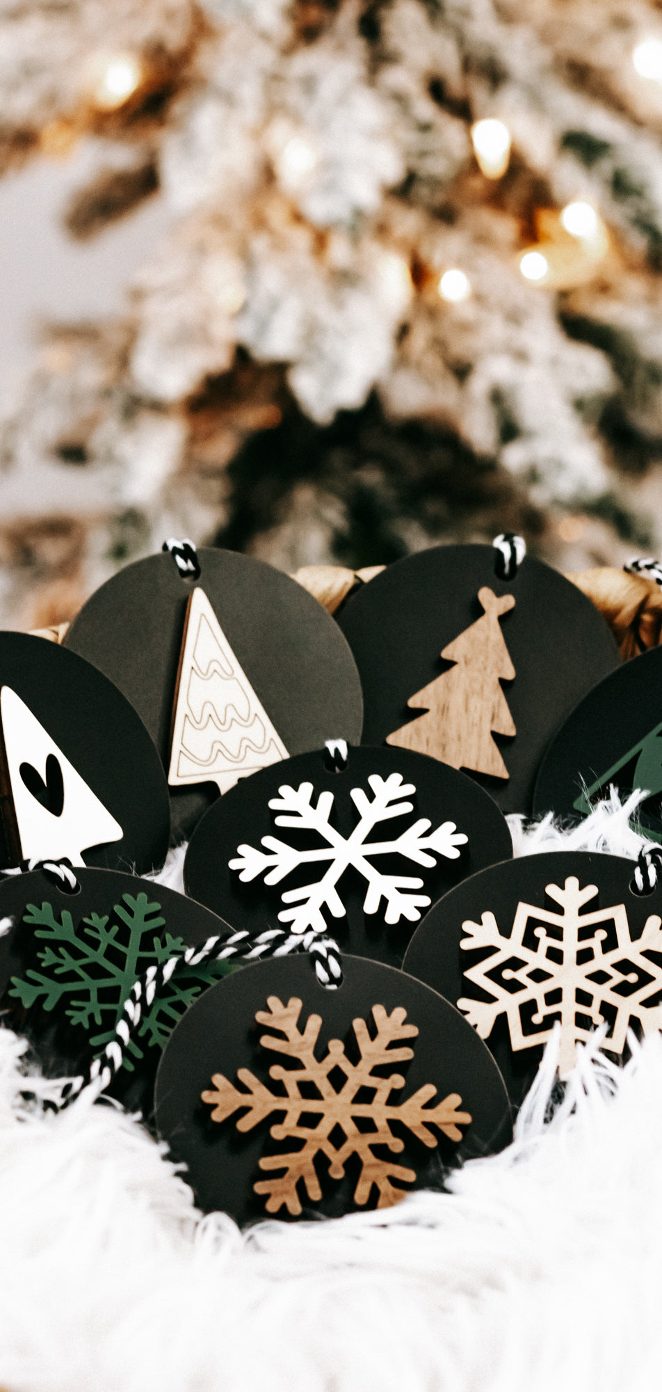 Black wooden ornament discs with tree and snowflakes in white, tan, and green, hanging loops
