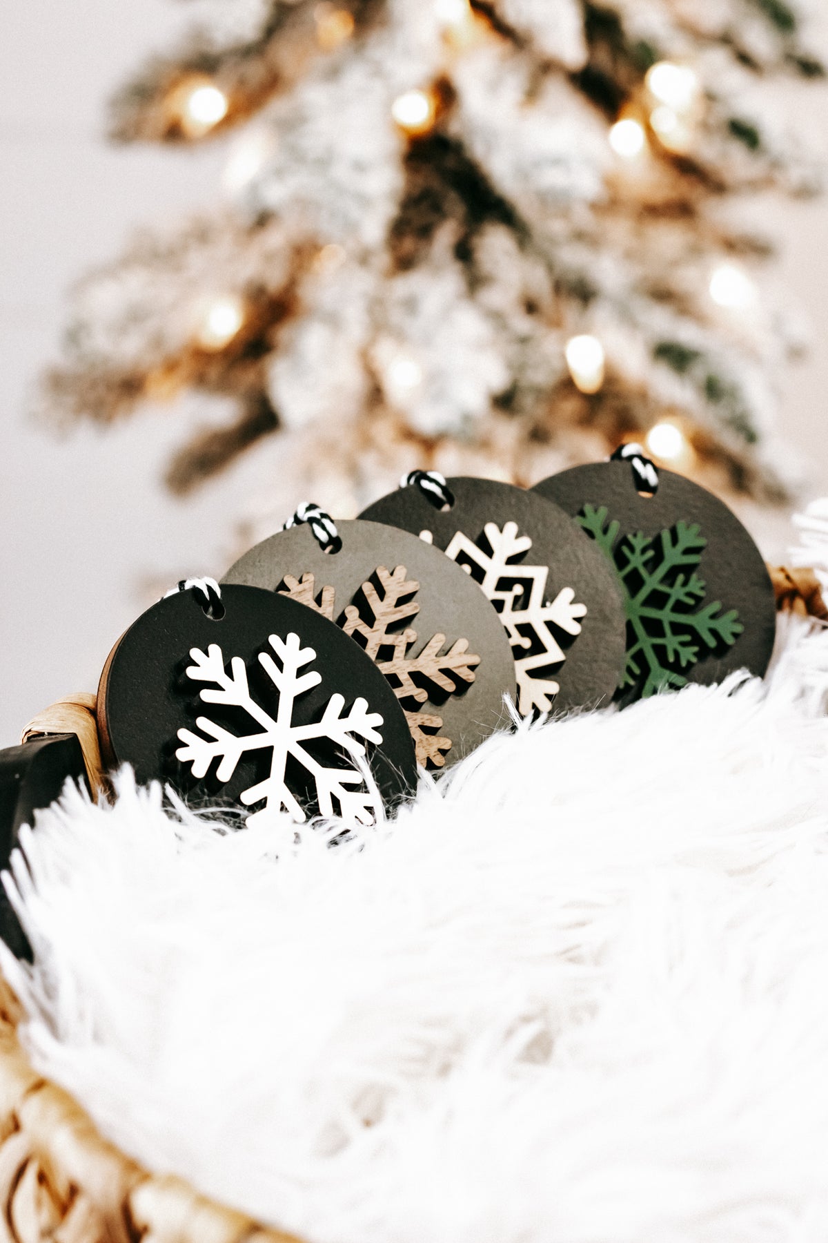 Black wooden ornament discs with white, green, and tan snowflakes, hanging loops