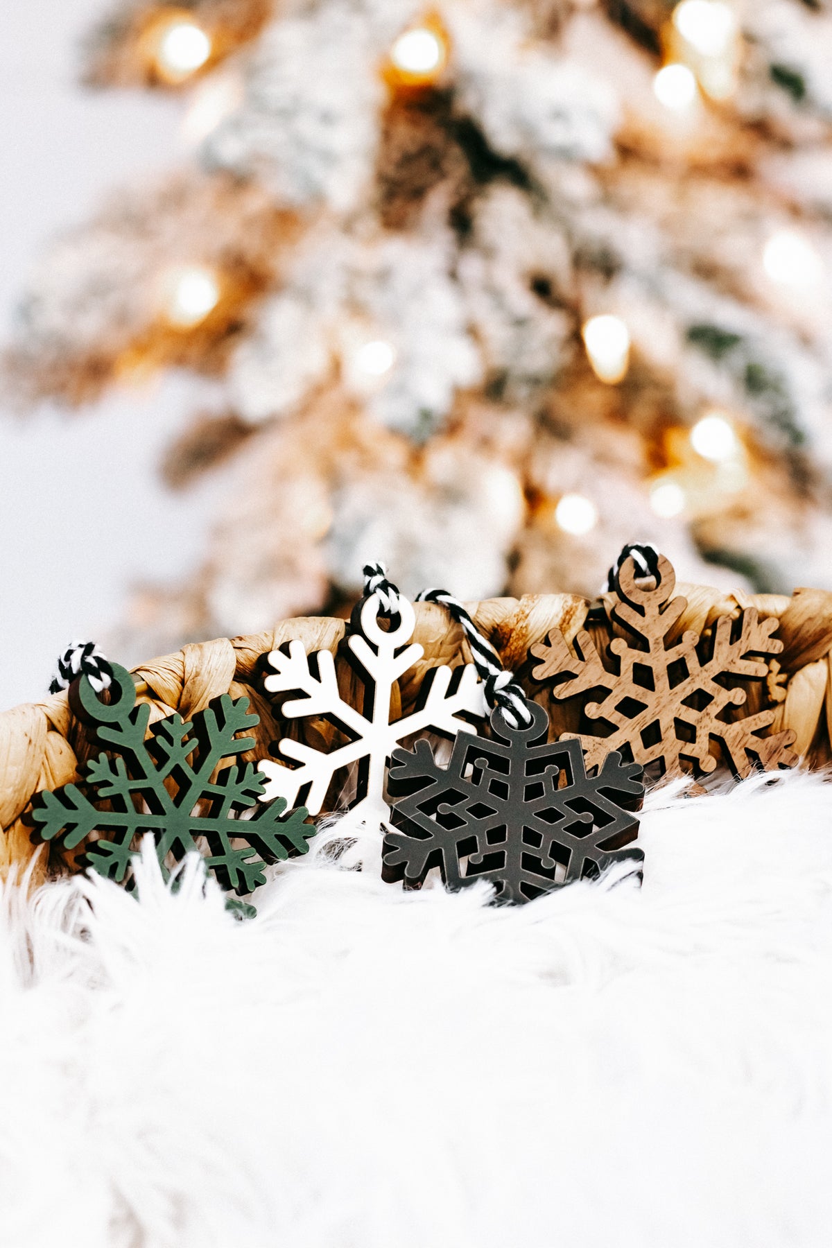 Set of mixed-color snowflake ornaments with braided string loops in a straw basket