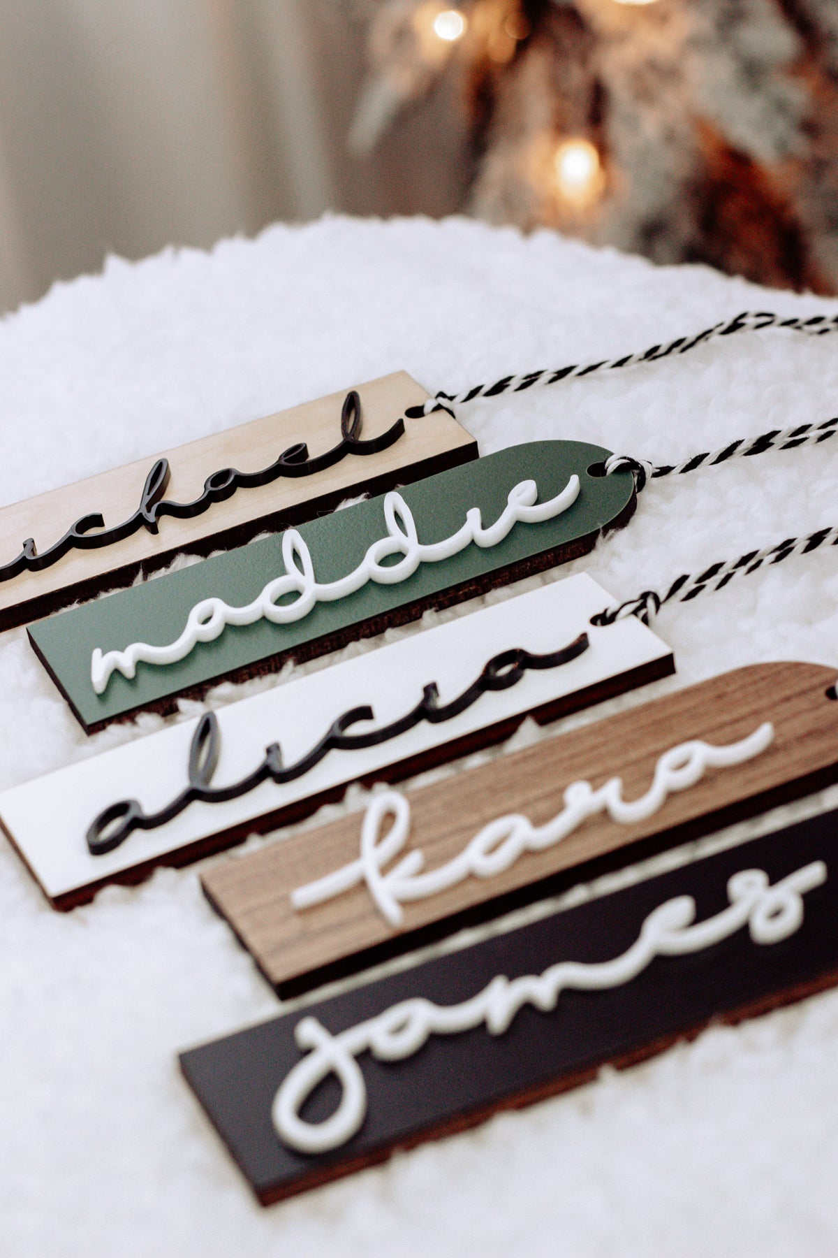 Close-up of stacked personalized stocking name tags in green, white, and dark tones