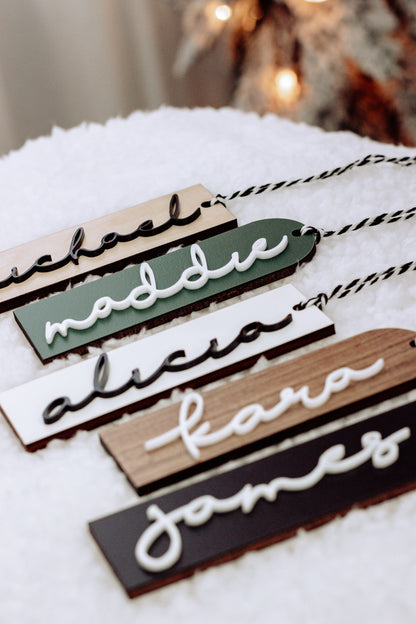 Close-up of stacked personalized stocking name tags in green, white, and dark tones