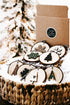 Rustic wood slice ornament set in kraft box with snowflake and tree designs, on strings