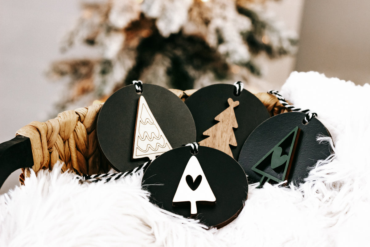 Set of black Christmas ornament discs with white tree outline and hanging loops