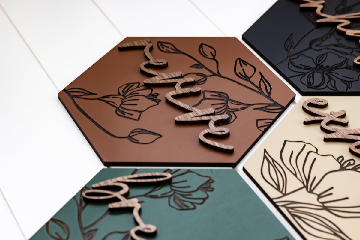 Close-up of engraved hexagon wooden wall art with floral linework and raised script