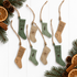 Engraved wooden stocking ornaments hanging with twine, green and wood tones on a white background