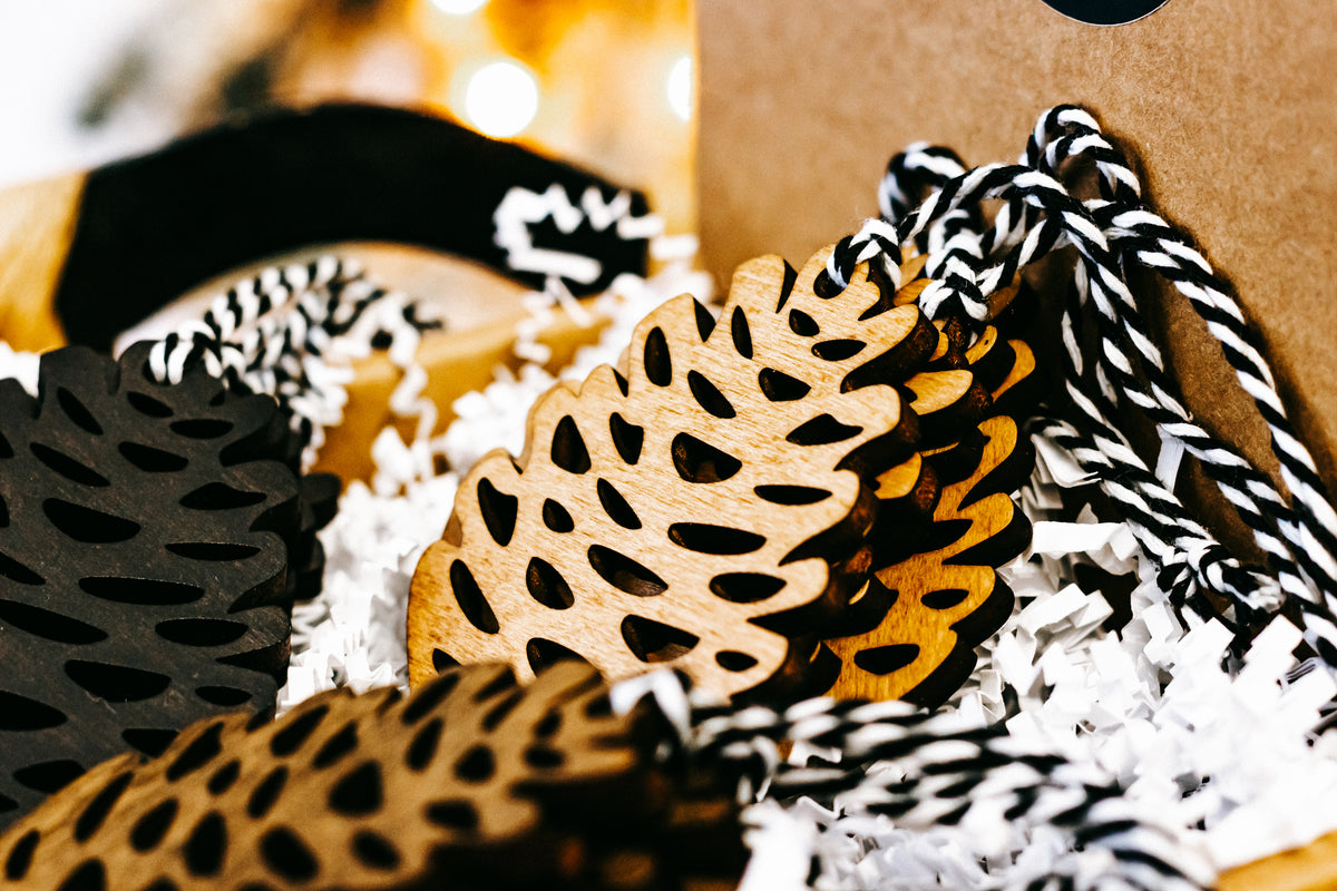 Hand-stained wooden pinecone ornaments with striped twine hangers, black and amber tones