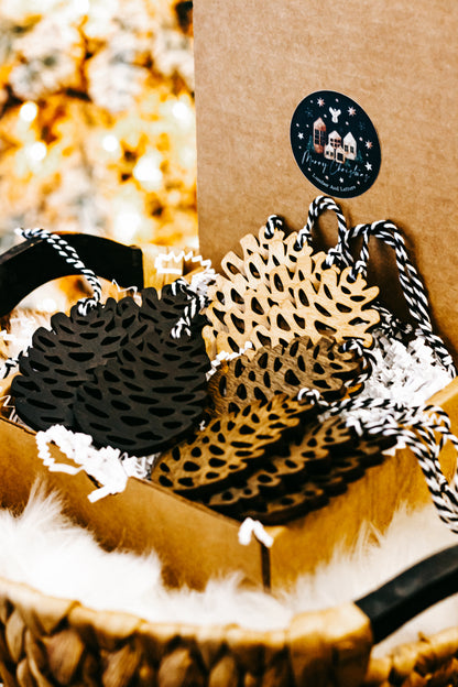 Hand-stained wooden pinecone ornaments with striped twine hangers in black, amber, and natural