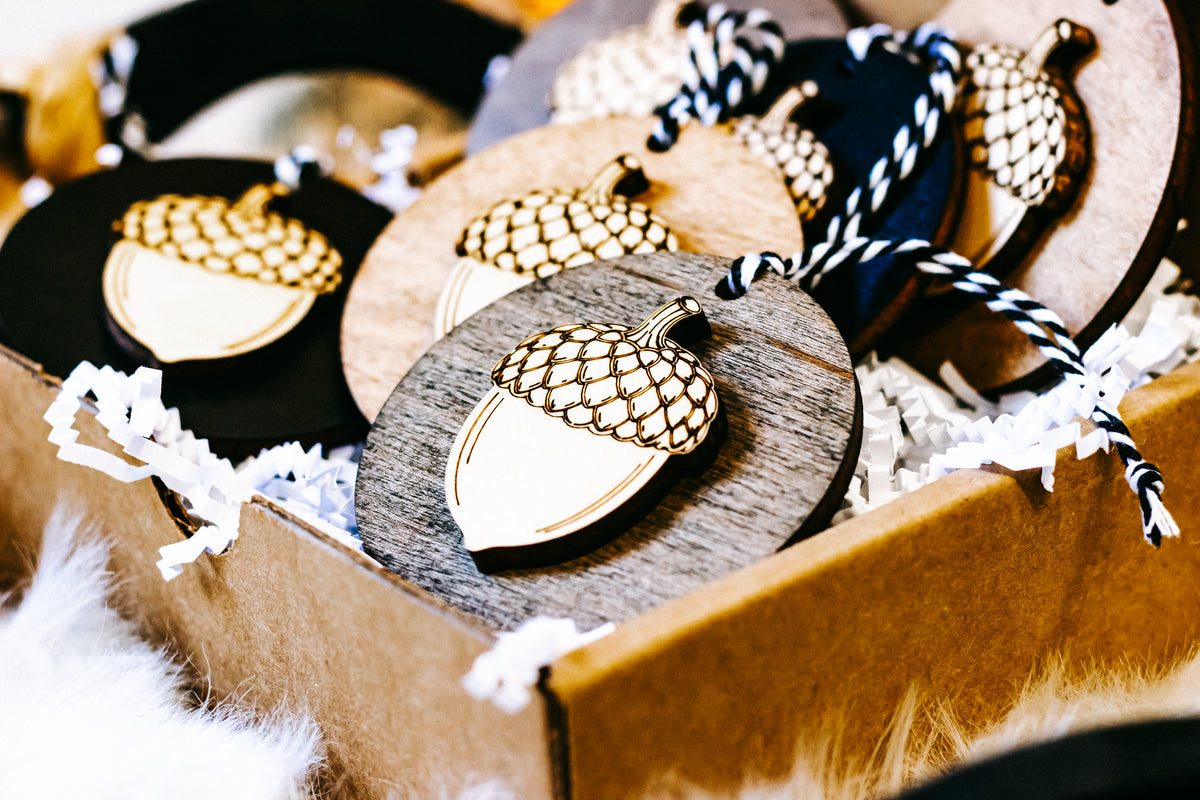 Cluster of round acorn ornaments in wood and black discs with gold checkered caps and twine.