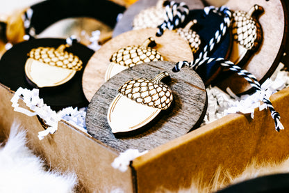 Cluster of round acorn ornaments in wood and black discs with gold checkered caps and twine.