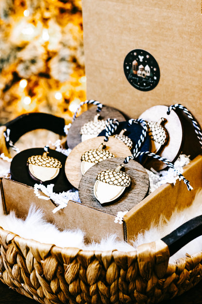 Assorted round acorn ornaments with gold checkered caps on wood and black discs, twine ties.