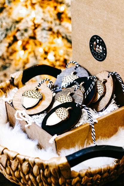 Tray of round acorn ornaments with gold checkered caps on black and wood bases, twine loops.