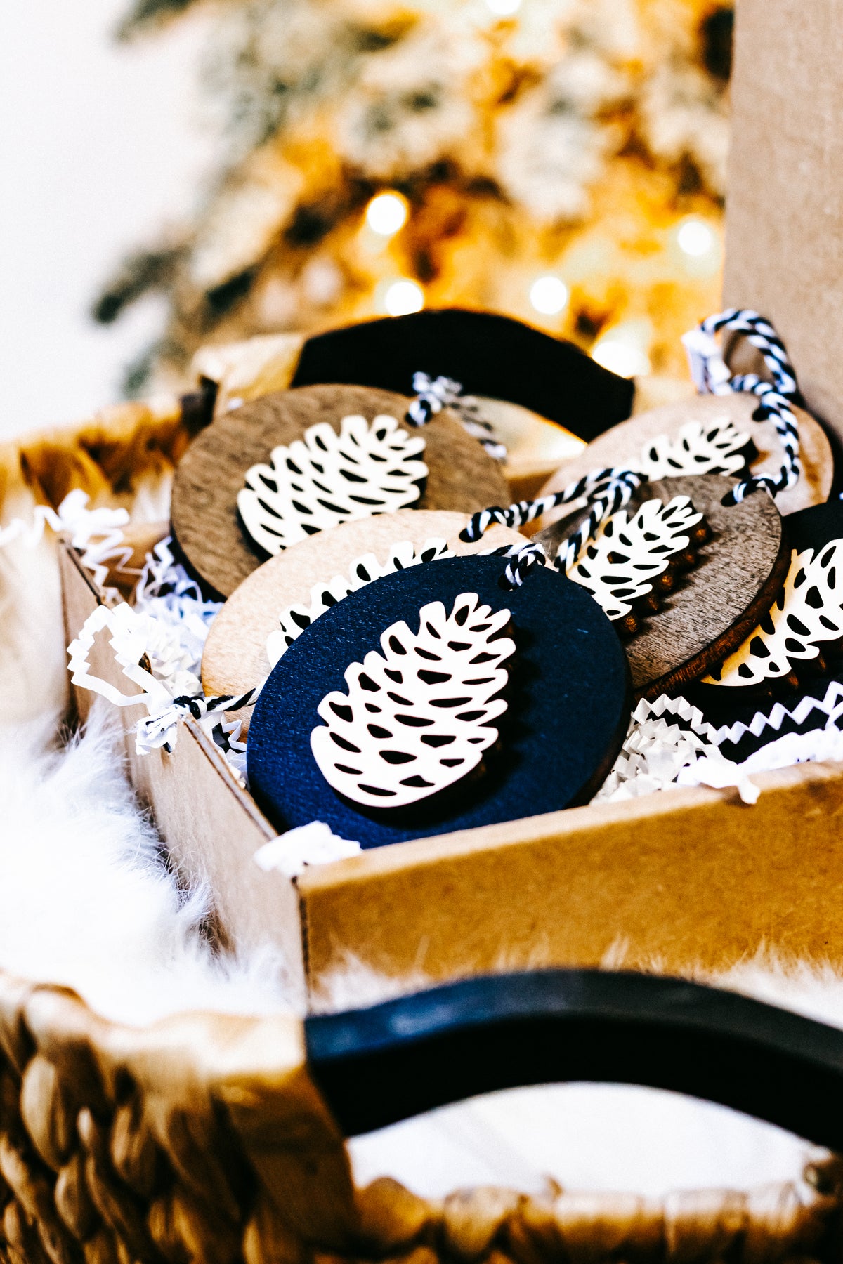 Wooden pinecone ornaments in a box, twine-hung round discs with white pinecone cutouts