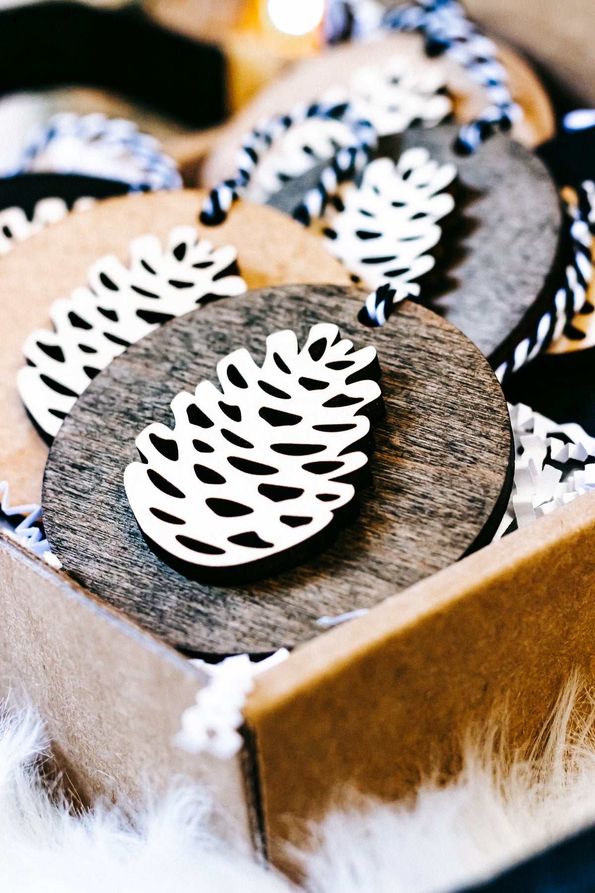 Wooden pinecone ornament close-up, gray wood disc with white pinecone cutout