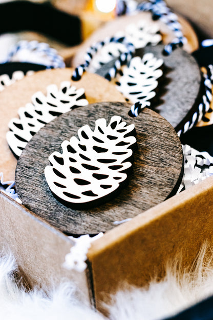Wooden pinecone ornament close-up, gray wood disc with white pinecone cutout