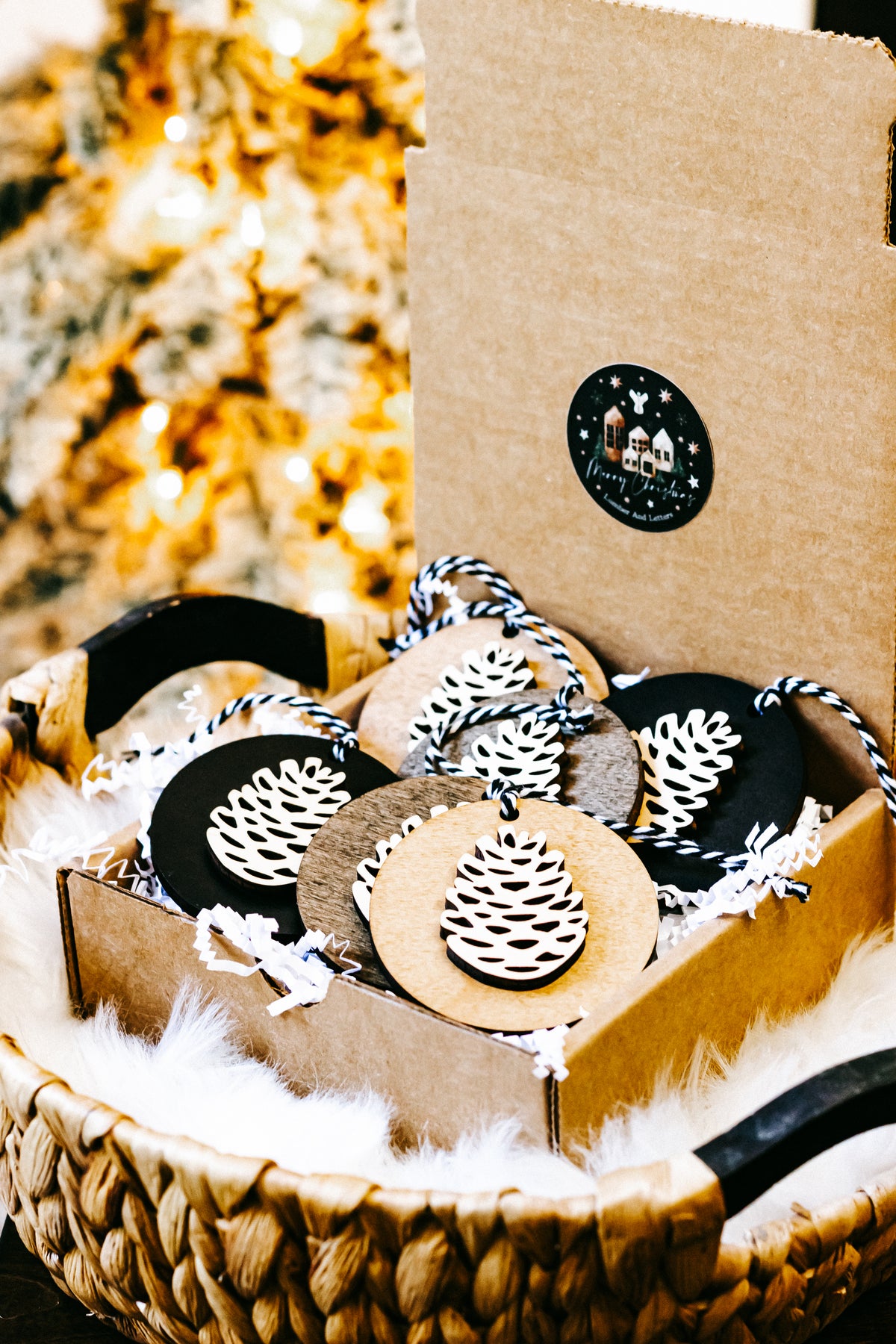 Wooden pinecone ornaments in box, round discs with white pinecone cutouts and twine
