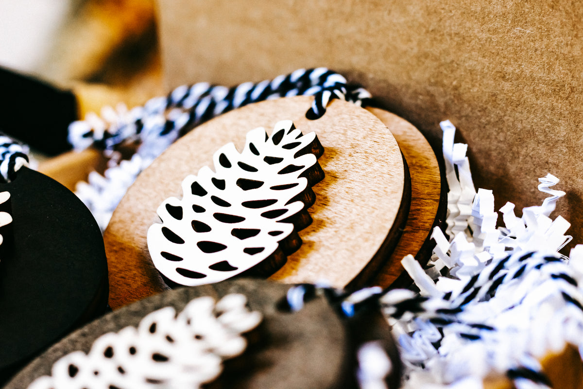 Wooden pinecone ornament close-up, natural wood and black round discs with white cutouts