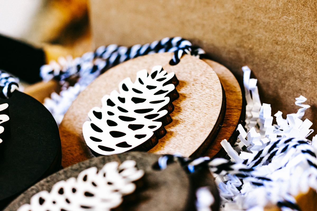Wooden pinecone ornament close-up, natural wood disc with white pinecone cutout
