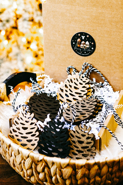 Assorted hand-stained wooden pinecone ornaments with striped twine hangers in a basket
