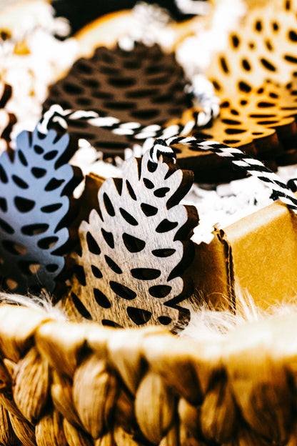 Close-up of hand-stained pinecone ornaments, speckled black and tan with hanging loops