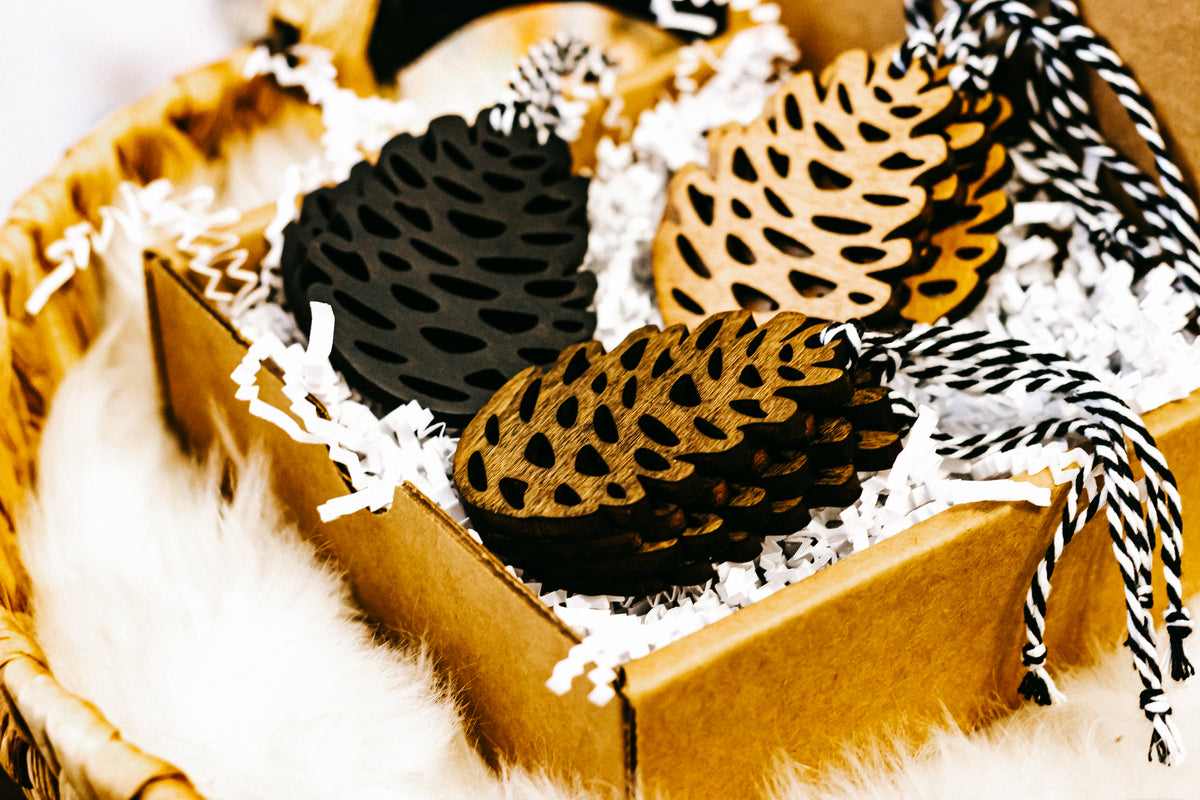 Close-up of hand-stained wooden pinecone ornaments with striped twine hangers