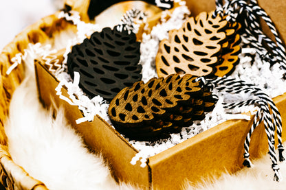 Close-up of hand-stained wooden pinecone ornaments with striped twine hangers