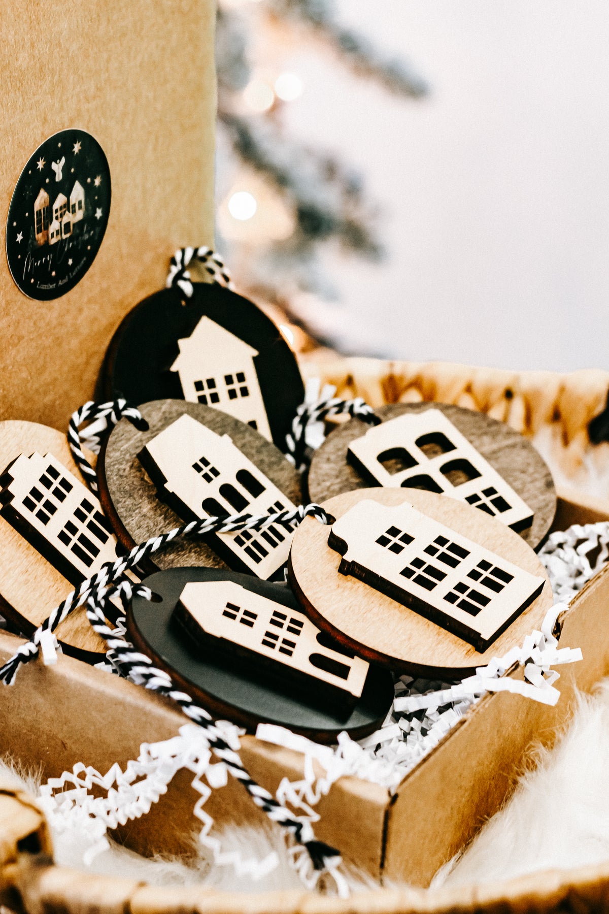Assorted round house ornaments nestled in a gift box with crinkled white filler