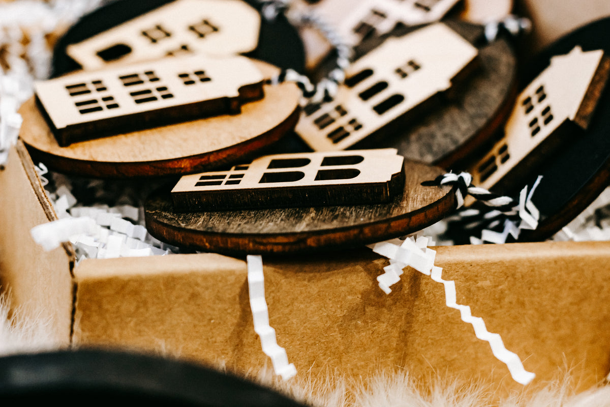 Close-up of stacked round house ornaments with window cutouts and striped cord ties