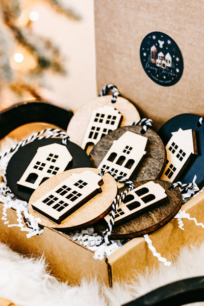 Assorted round house ornaments with striped cords, tucked in a kraft box with filler