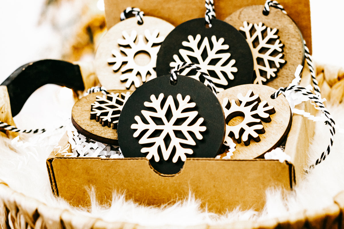 Layered snowflake ornaments in crate, black and light wood rounds with white snowflakes
