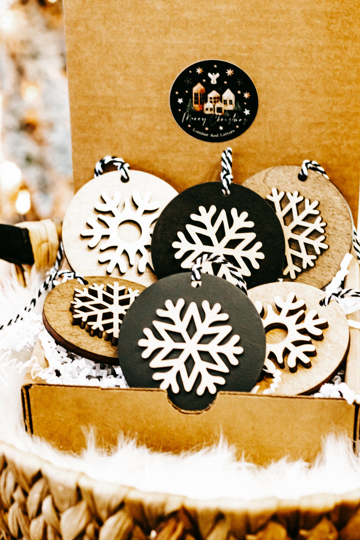 Layered snowflake ornaments in woven basket, black and light wood discs with white snowflakes