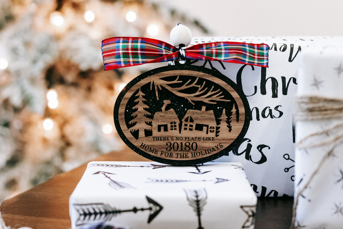 Round Christmas ornament with house scene, plaid bow, hanging loop; zip code 30180.