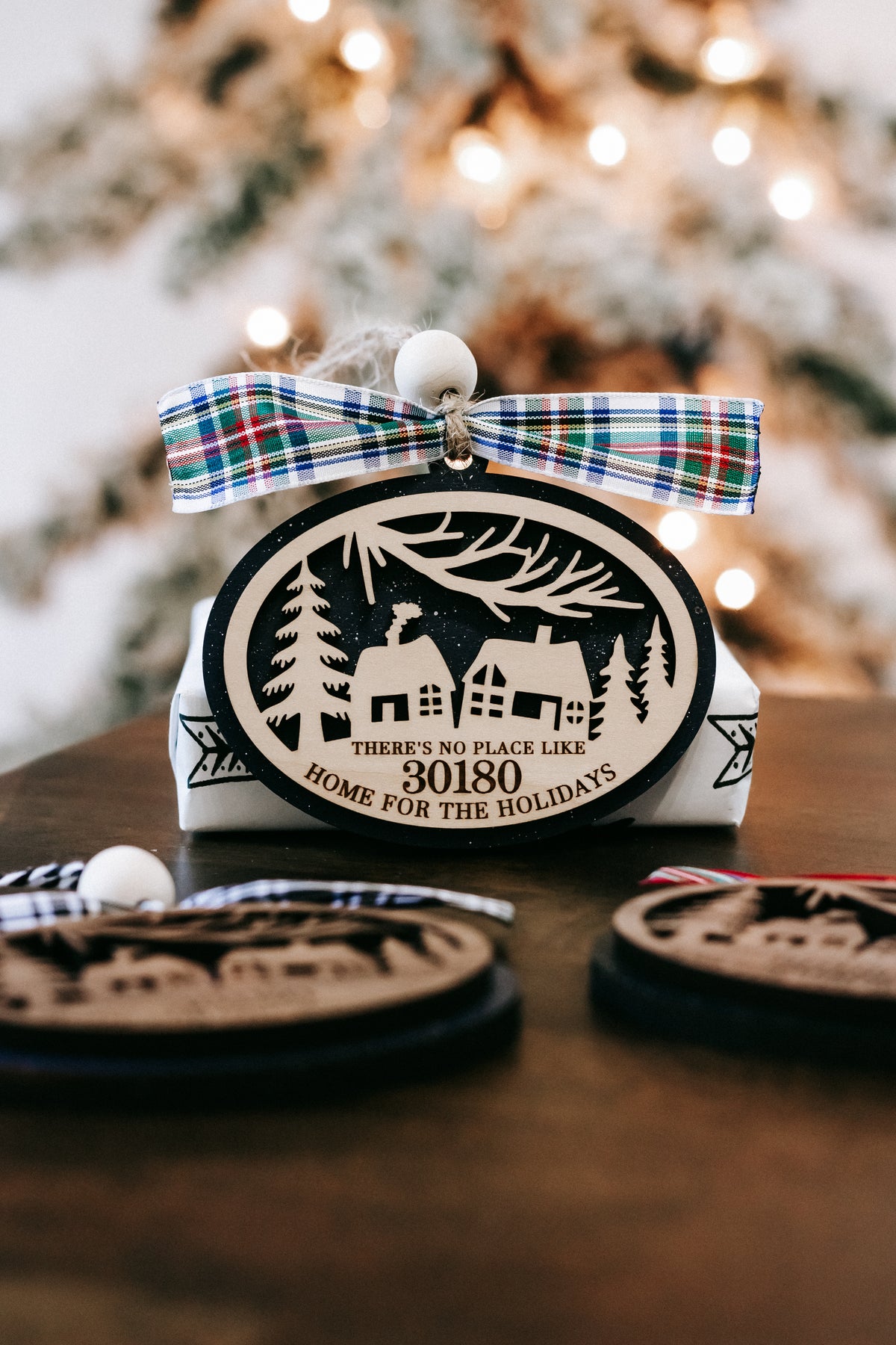 Plaid ribbon Christmas ornament with house graphic and zip code 30180, front view.