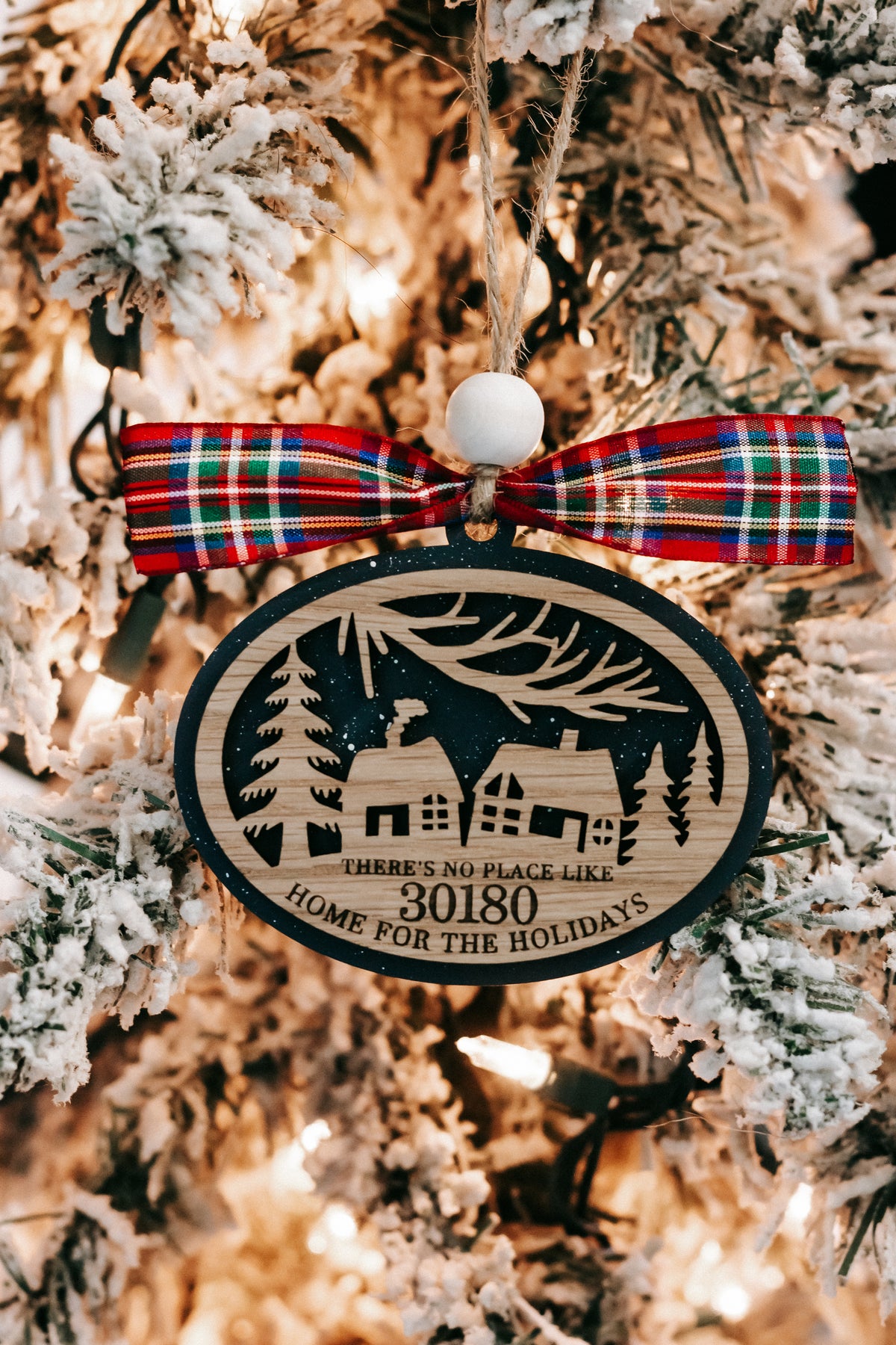 Round Christmas ornament on evergreen branches with plaid bow and zip code 30180, hanging.