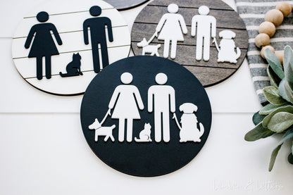 Two round restroom signs with pet silhouettes: dark navy and tan icons with white circles